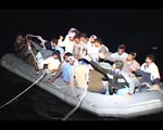 The coast guard's spotlight shines on a boat packed with migrants.